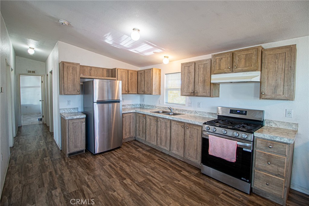 4444 East Ave R, Unit 202 Palmdale, CA 93552 - Photo 10 of 23 a kitchen with a refrigerator a sink and wooden cabinets