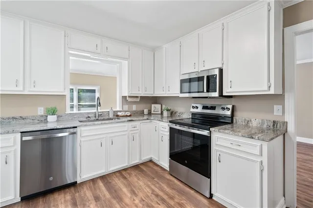 a kitchen with granite countertop white cabinets and white stainless steel appliances