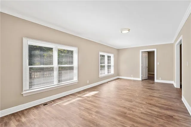 a view of an empty room with wooden floor and windows