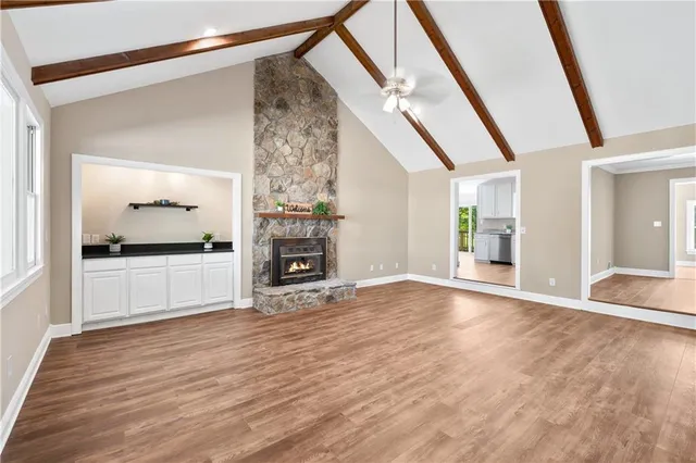 a view of an empty room with a window and kitchen view