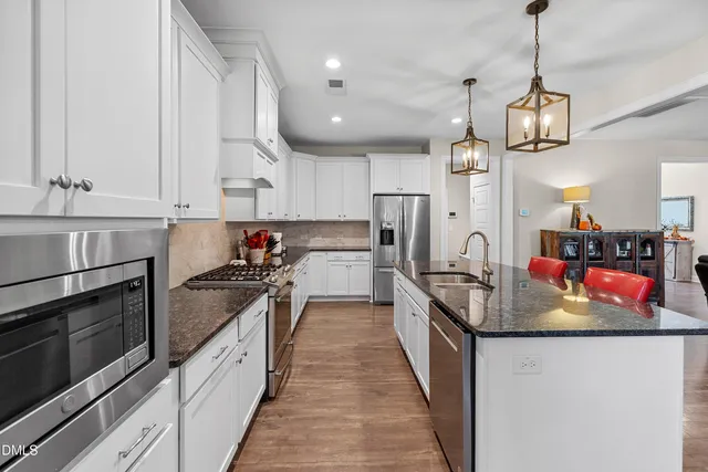 a kitchen with stainless steel appliances granite countertop a sink a stove and a refrigerator