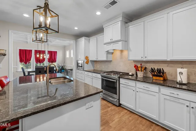 a kitchen with stainless steel appliances granite countertop a sink a stove and a wooden cabinets