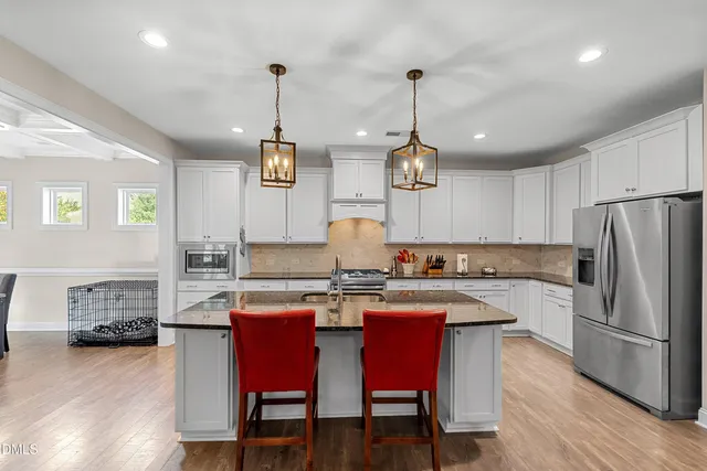 a kitchen with stainless steel appliances granite countertop a stove a refrigerator a kitchen island a dining table and chairs