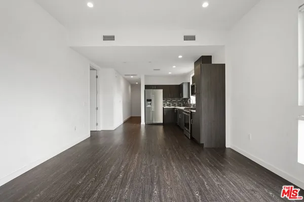 a view of a kitchen with a refrigerator and wooden floor