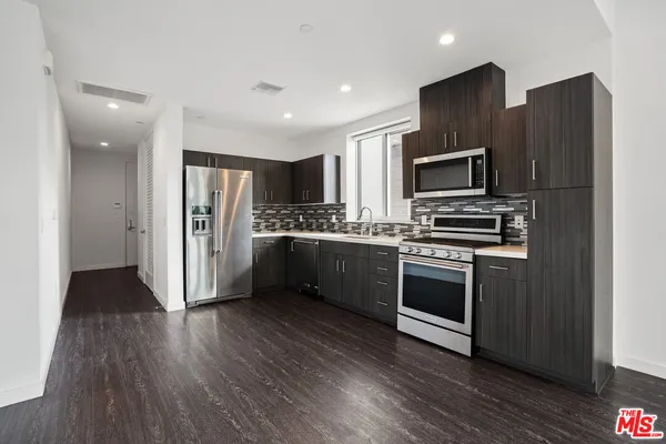 a kitchen with stainless steel appliances a refrigerator cabinets and wooden floor