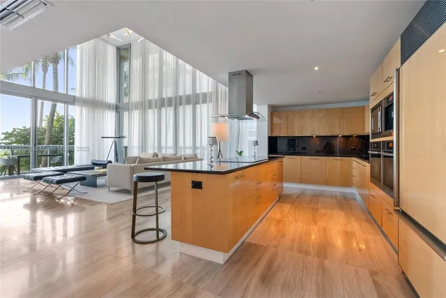 a large kitchen with kitchen island a large window a sink and stainless steel appliances