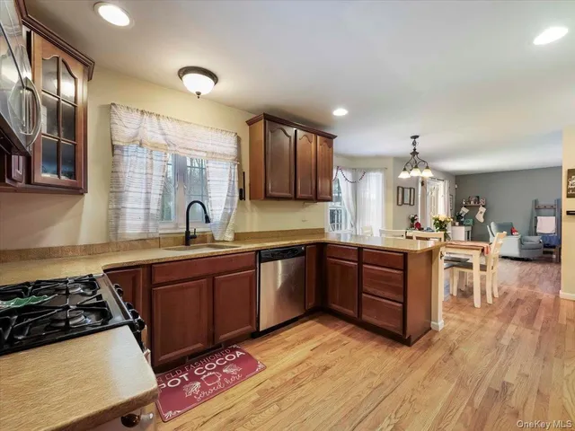 a large kitchen with stainless steel appliances granite countertop a sink dishwasher stove and wooden cabinets