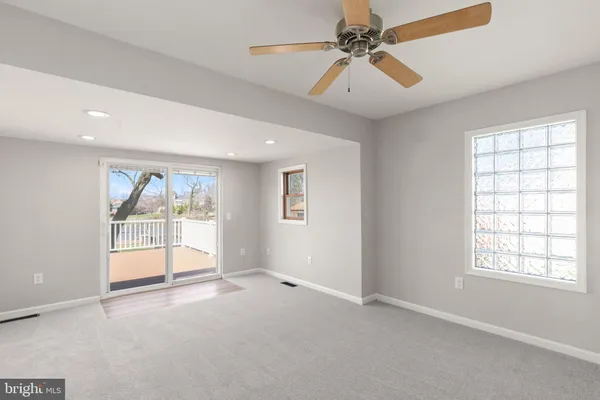 an empty room with windows and chandelier fan