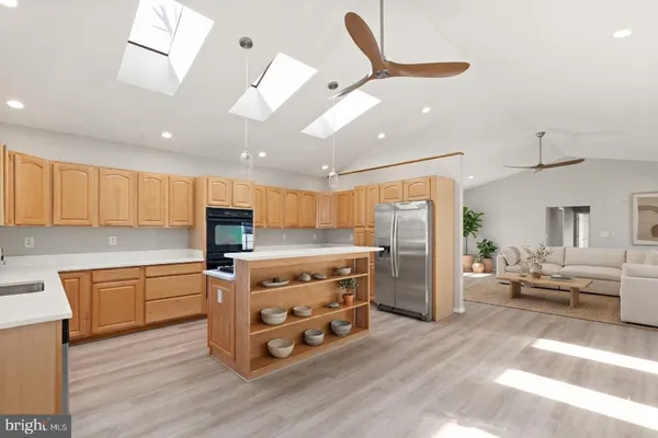 a kitchen with stainless steel appliances kitchen island granite countertop a refrigerator a stove top oven a sink with island and chairs