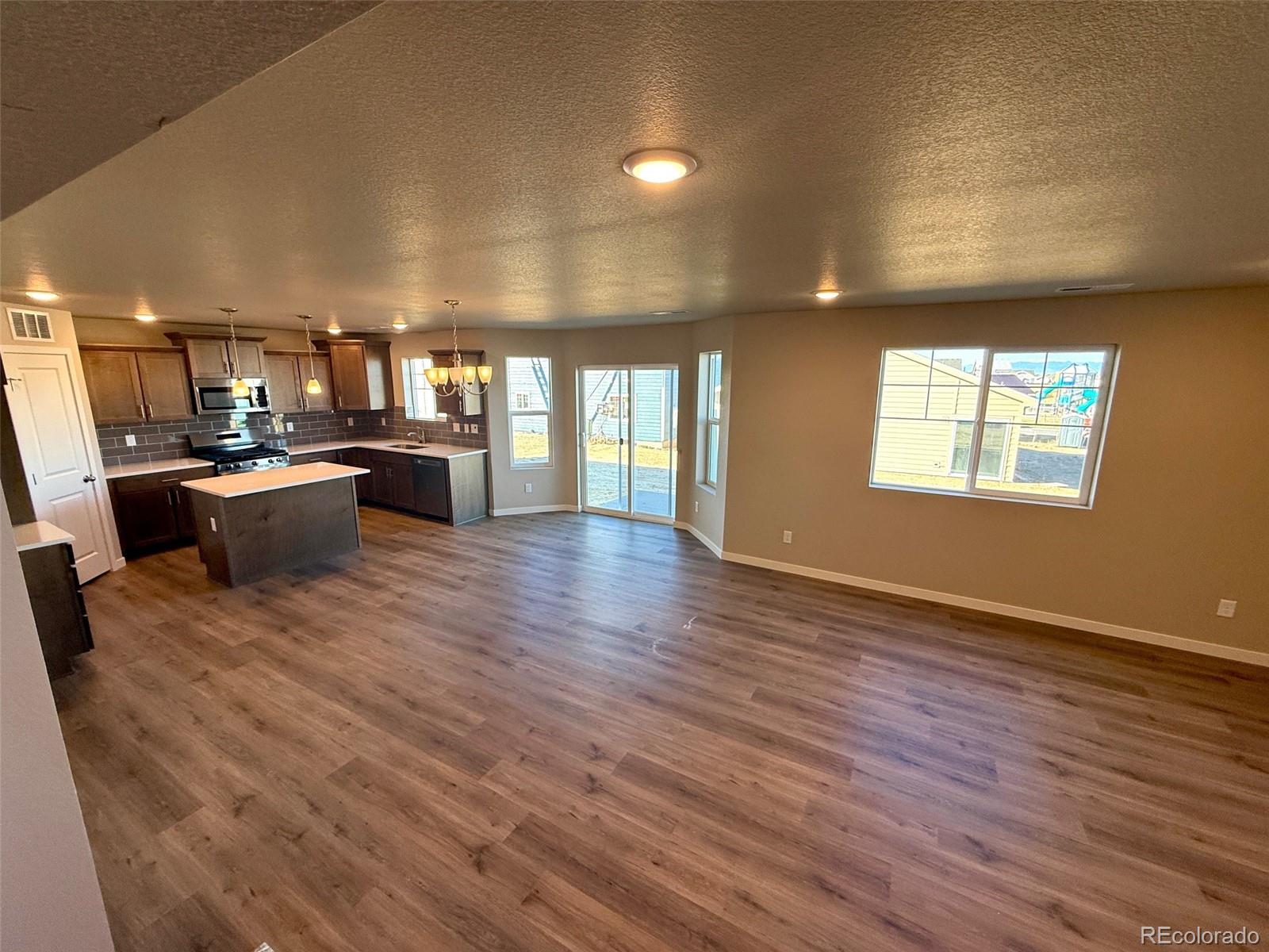 757 North Clubview Street Watkins, CO 80137 - Photo 8 of 24 wooden floor with kitchen view and a window