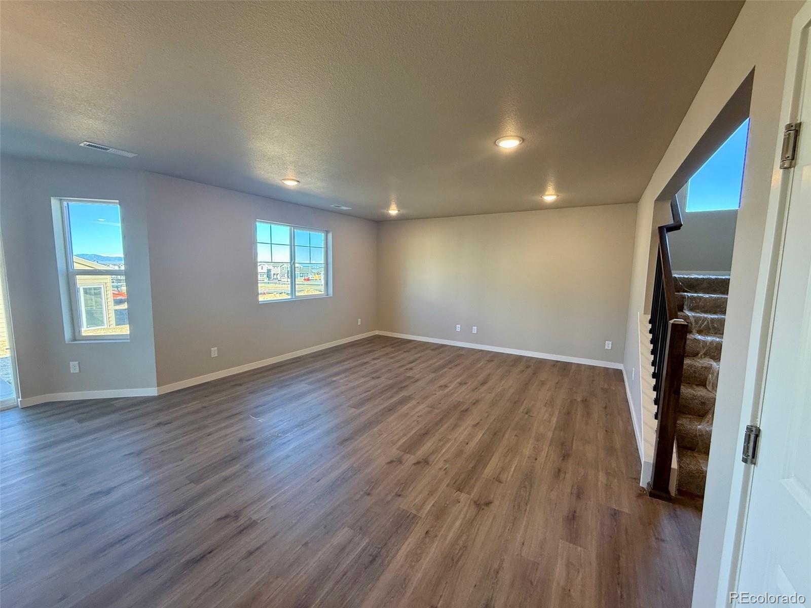 757 North Clubview Street Watkins, CO 80137 - Photo 9 of 24 an empty room with wooden floor and windows