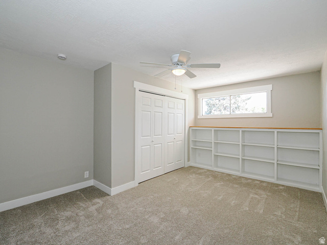 154 East 3000th Street South Bountiful, UT 84010 - Photo 21 of 37 Spacious room featuring neutral carpeting, a ceiling fan, a built-in closet with bifold doors, and extensive built-in shelving with a light wood-finish top