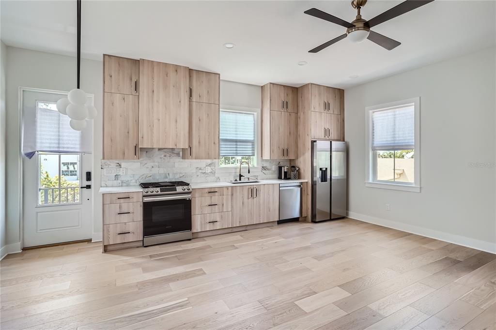 325 33rd Avenue North St. Petersburg, FL 33704 - Photo 48 of 57 a large white kitchen with stainless steel appliances granite countertop a stove a sink and white cabinets with wooden floor