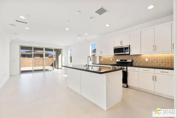 a kitchen with granite countertop a stove top oven a sink a counter space and cabinets