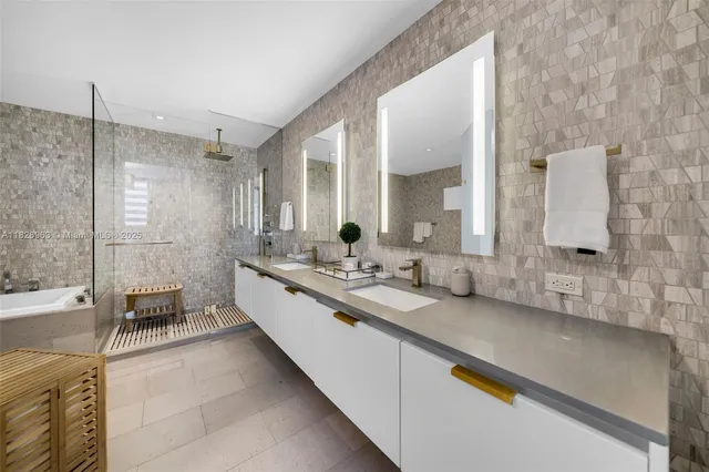 a large white bathroom with a double vanity sink a mirror and a bathtub