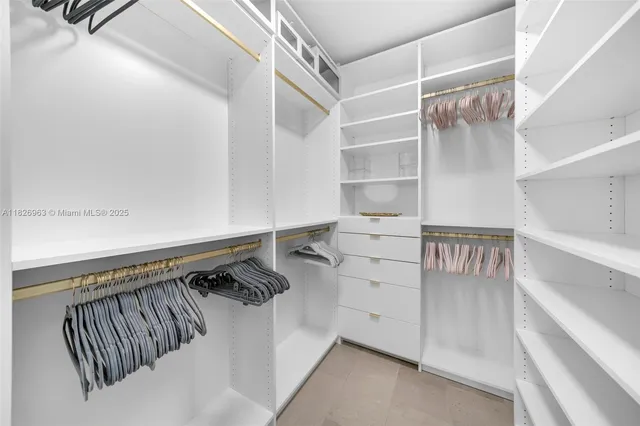 a view of walk in closet with clothes and shoes