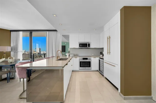 a kitchen with stainless steel appliances a sink a stove a refrigerator cabinets and a window