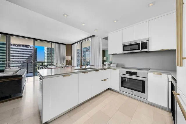 a kitchen with stainless steel appliances granite countertop a stove top oven a sink and a microwave