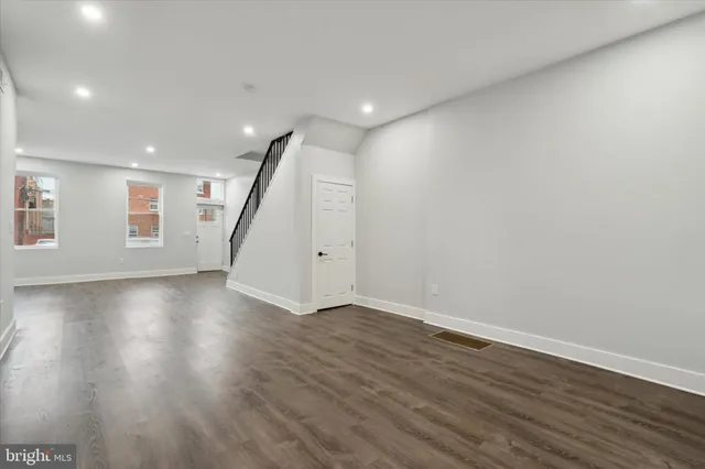an empty room with wooden floor and staircase