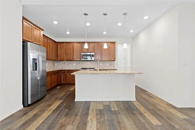 a view of kitchen with granite countertop refrigerator oven a sink and white cabinets with wooden floor