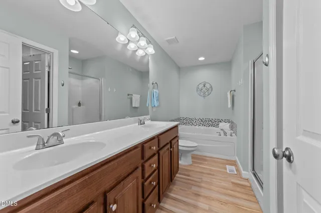 a spacious bathroom with a granite countertop sink a toilet a mirror and shower