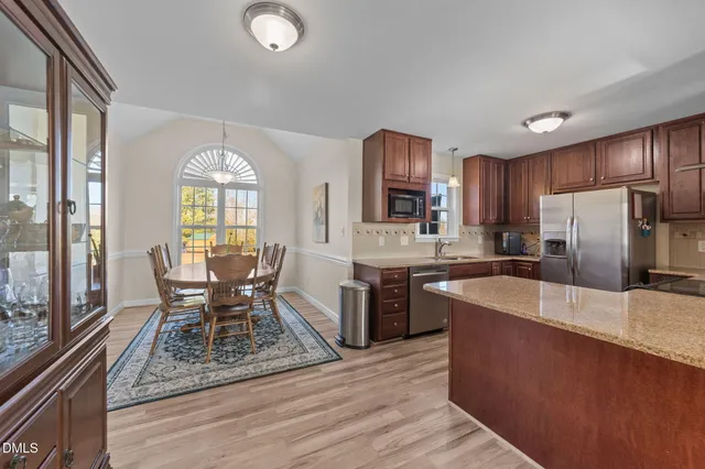 a kitchen with stainless steel appliances granite countertop a stove a sink dishwasher a refrigerator and wooden cabinets with wooden floor