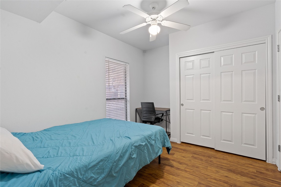 2515 Pearl Street, Unit 102 Austin, TX 78705 - Photo 19 of 30 Bedroom featuring wood finished floors, a closet, a desk, and ceiling fan