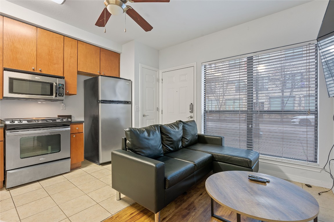 2515 Pearl Street, Unit 102 Austin, TX 78705 - Photo 25 of 30 Kitchen featuring brown cabinetry, appliances with stainless steel finishes, light tile patterned floors, and dark countertops