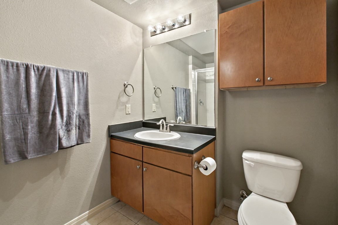 2515 Pearl Street, Unit 102 Austin, TX 78705 - Photo 3 of 30 Full bathroom featuring a textured wall, vanity, light tile patterned floors, and a shower stall