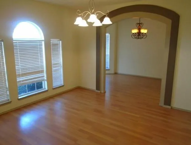 a view of a room with wooden floor chandelier and windows