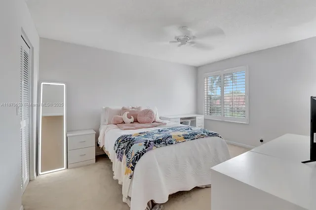 a bed sitting in a bedroom next to a window and a chandelier