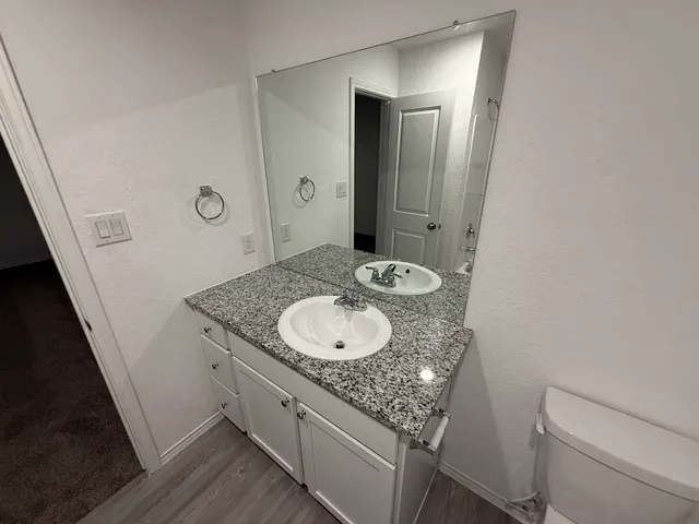 a bathroom with a granite countertop sink a toilet and a mirror