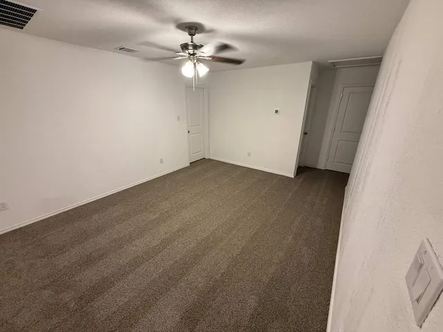 an empty room with a chandelier fan and wooden floor