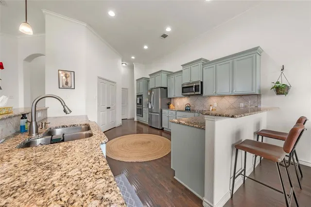 a kitchen with sink a refrigerator and chairs