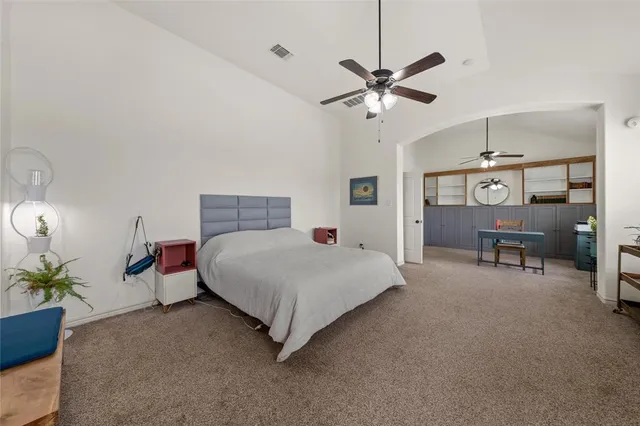 a bedroom with a bed a chandelier and potted plant on the dresser