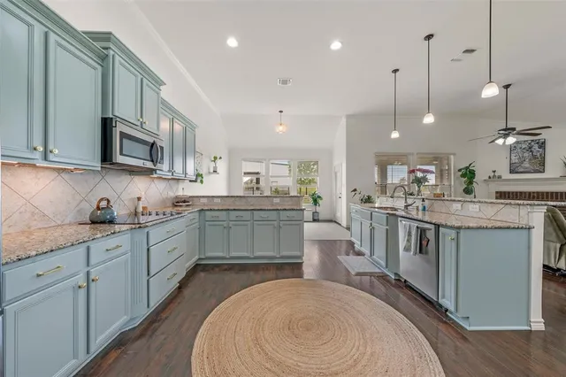 a kitchen with kitchen island granite countertop a sink a counter top space stainless steel appliances and cabinets