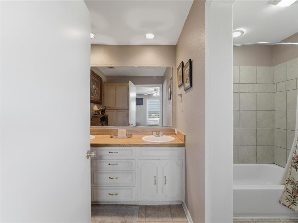 301 Ovilla Road Waxahachie, TX 75167 - Photo 25 of 38 a bathroom with a double vanity sink a mirror and a bathtub