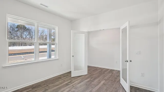 a view of an empty room with wooden floor and a window