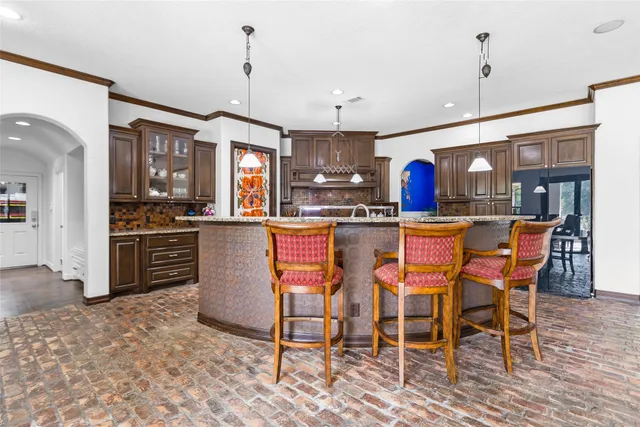 a kitchen with stainless steel appliances granite countertop a stove top oven a refrigerator a dining table and chairs with wooden floor