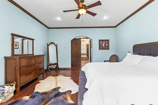 a bedroom with a bed a dresser and wooden floor