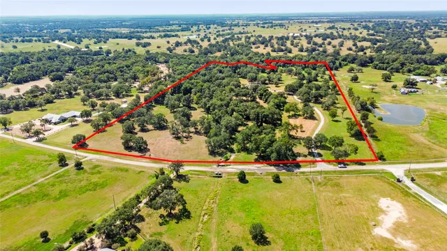 an aerial view of residential houses with outdoor space and trees all around
