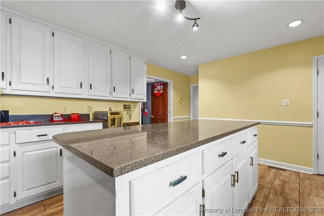 a kitchen with stainless steel appliances granite countertop a sink dishwasher and white cabinets with wooden floor