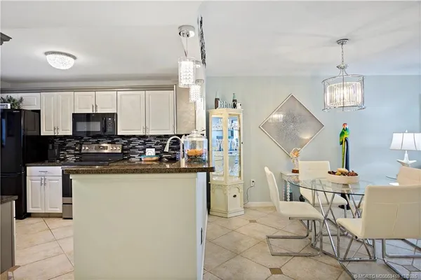 a kitchen with stainless steel appliances kitchen island granite countertop a sink a stove a refrigerator cabinets and chairs