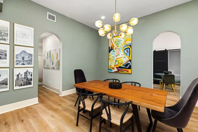 a dining room with chandelier and wooden floor
