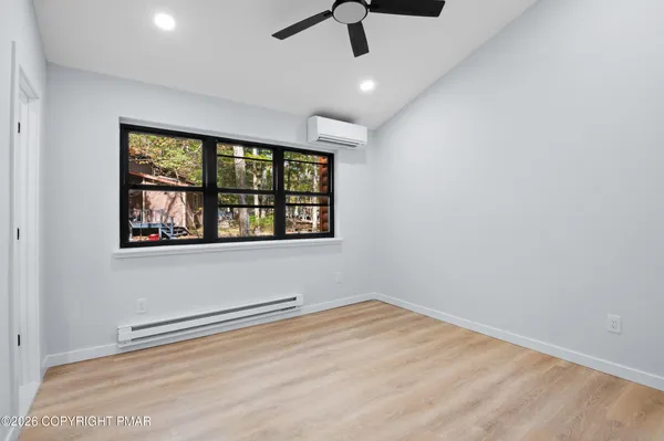 an empty room with ceiling fan and windows