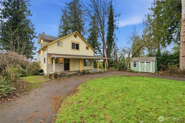 a front view of a house with garden and trees