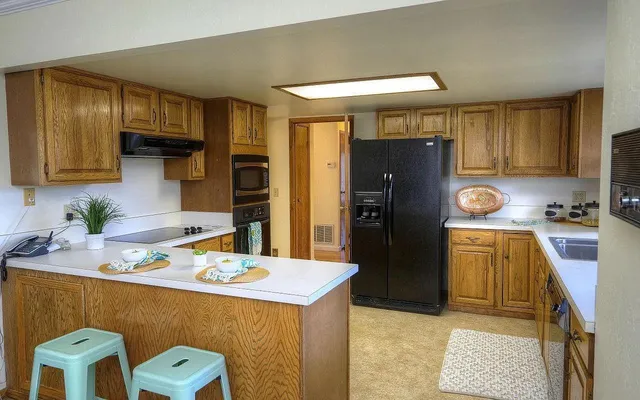 a kitchen with stainless steel appliances granite countertop a refrigerator a stove and a sink