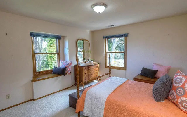 a bedroom with a bed and large windows