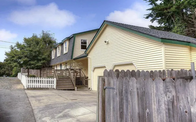 a view of a house with a small yard and wooden fence