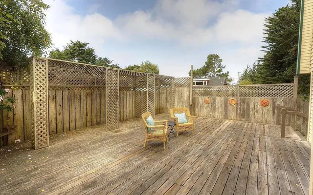 a view of a roof deck with table and chairs with wooden floor and fence